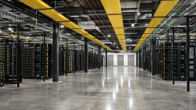 Illustration. Wide view of a data hall with rows of open server racks on both sides, yellow overhead busway and cable tray, and a bare polished floor down the center aisle.